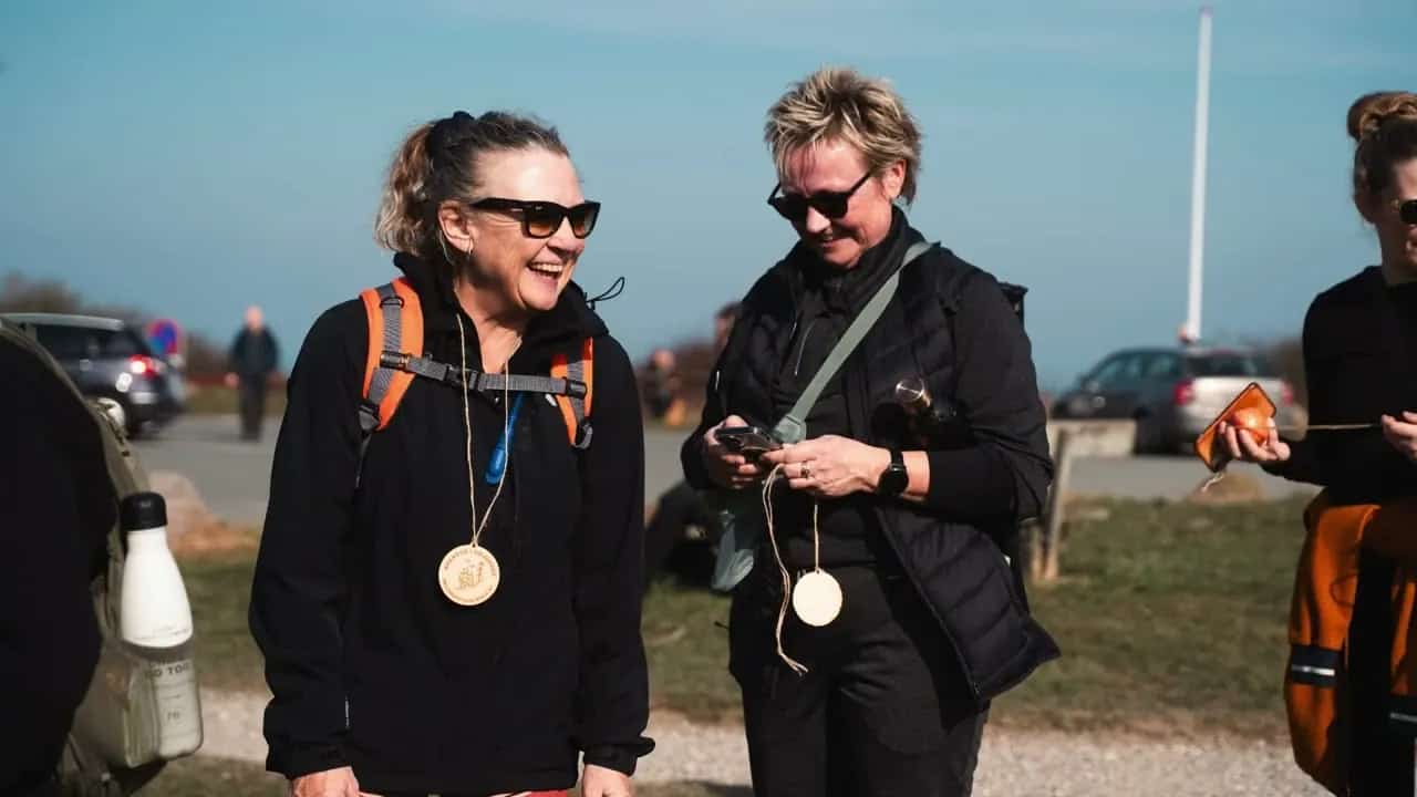 To deltagere smiler og kigger på deres medaljer efter at være kommet i mål