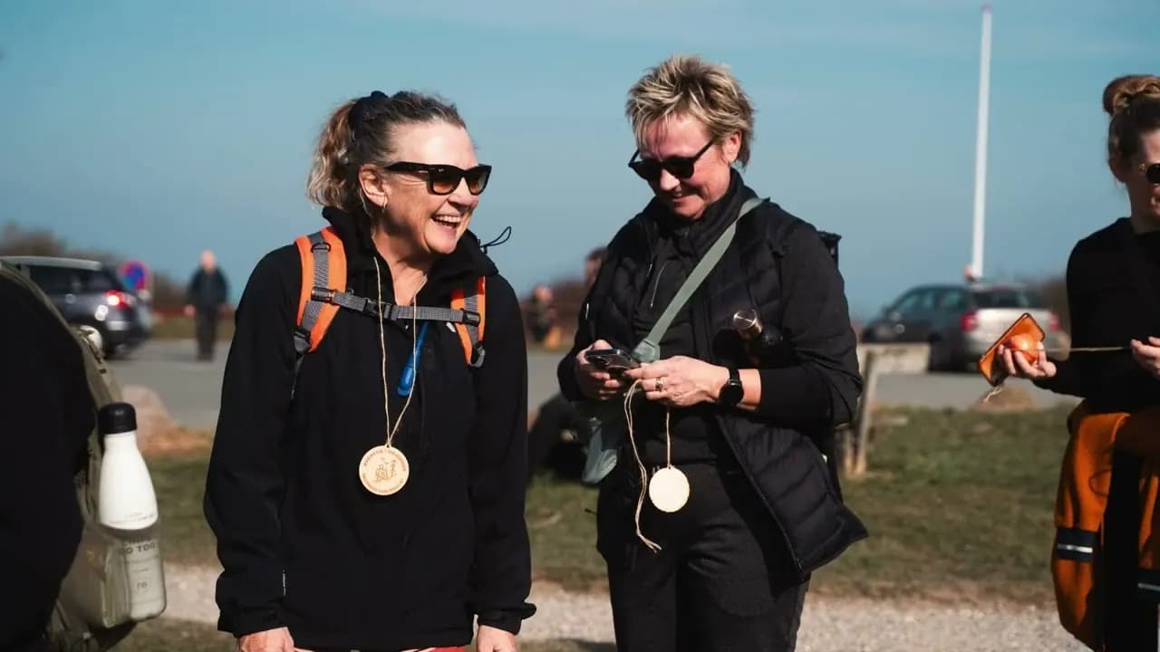 To deltagere smiler og kigger på deres medaljer efter at være kommet i mål
